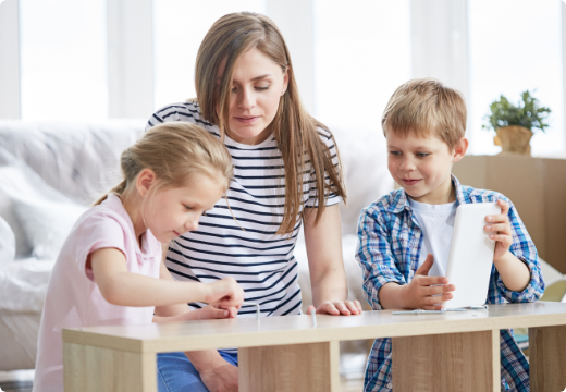 Mujer y sus dos hijos pintando en una sala.